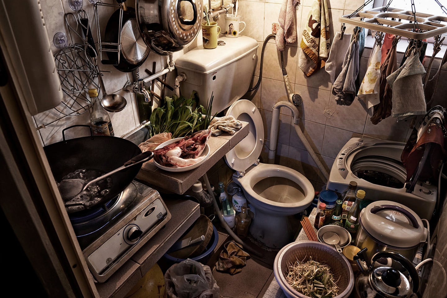 There is no word in this picture. It shows cooking, using the washroom and washing the clothes in the tiny living space.