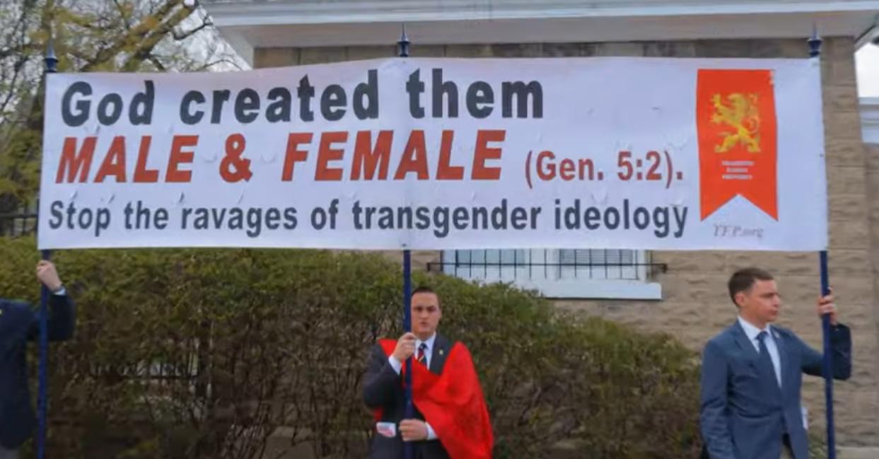 protesters holding up a sign saying "God created them MALE & FEMALE (gen. 5:2). Stop the ravages of the transgender ideology"