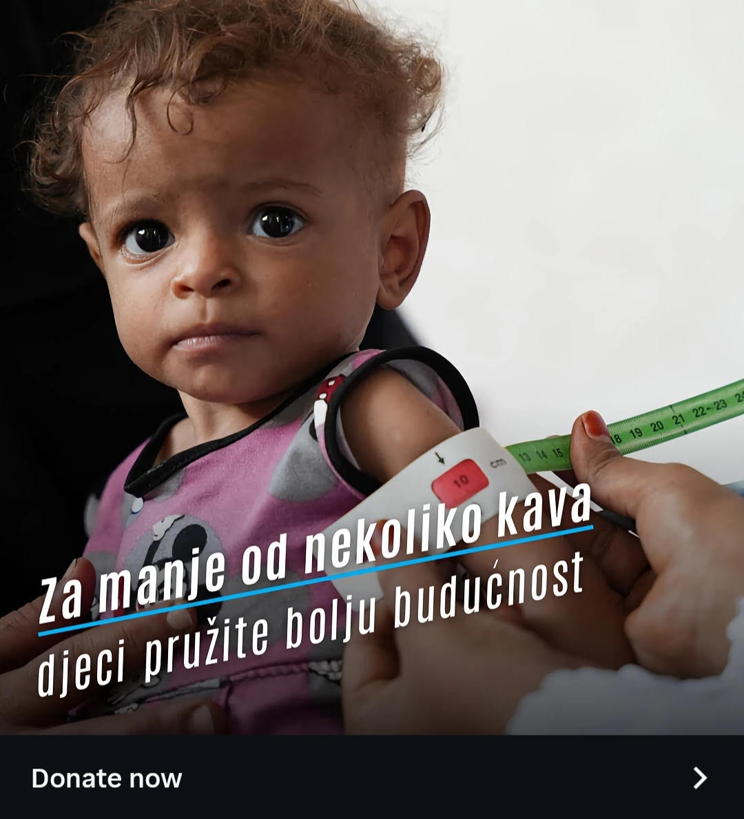 An advertisement featuring a close-up of a young child with wide eyes looking toward the camera. A person's hands are visible using a green and white mid-upper arm circumference (MUAC) measuring tape to check the child's upper arm.  Large text in Croatian overlaying the image reads: "Za manje od nekoliko kava djeci pružite bolju budućnost". Below the image, there is a dark banner with the text "Donate now" alongside a right-pointing arrow icon.
